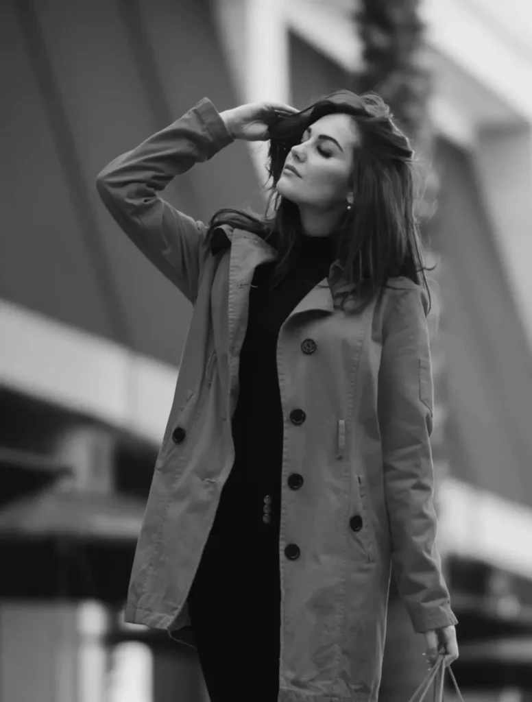 Woman in a long belted coat, photographed in black and white